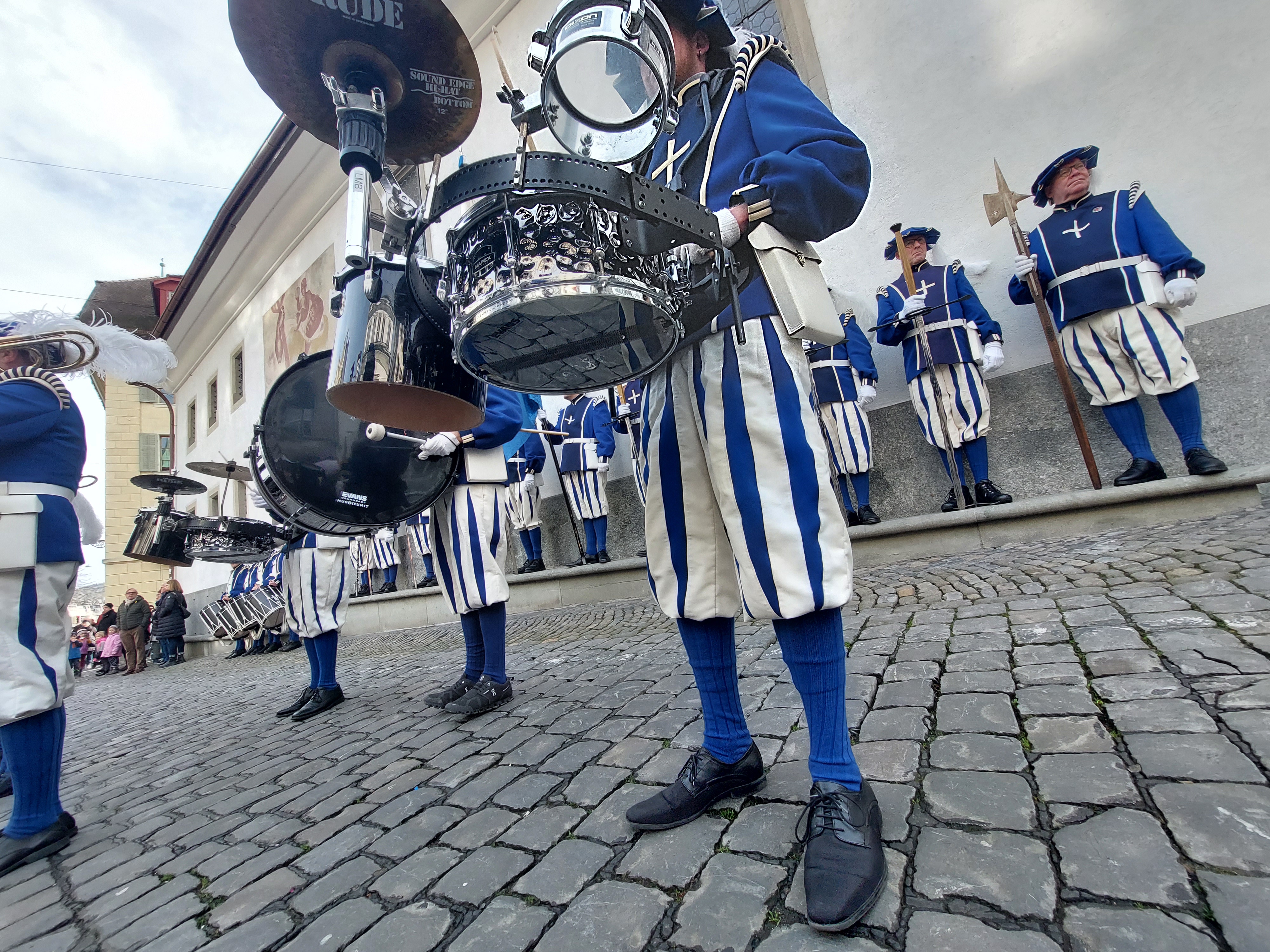 Zwei Schlagzeuger und ein Tambour stehen in den hinteren Reihen der Lucerne Marching Band Formation