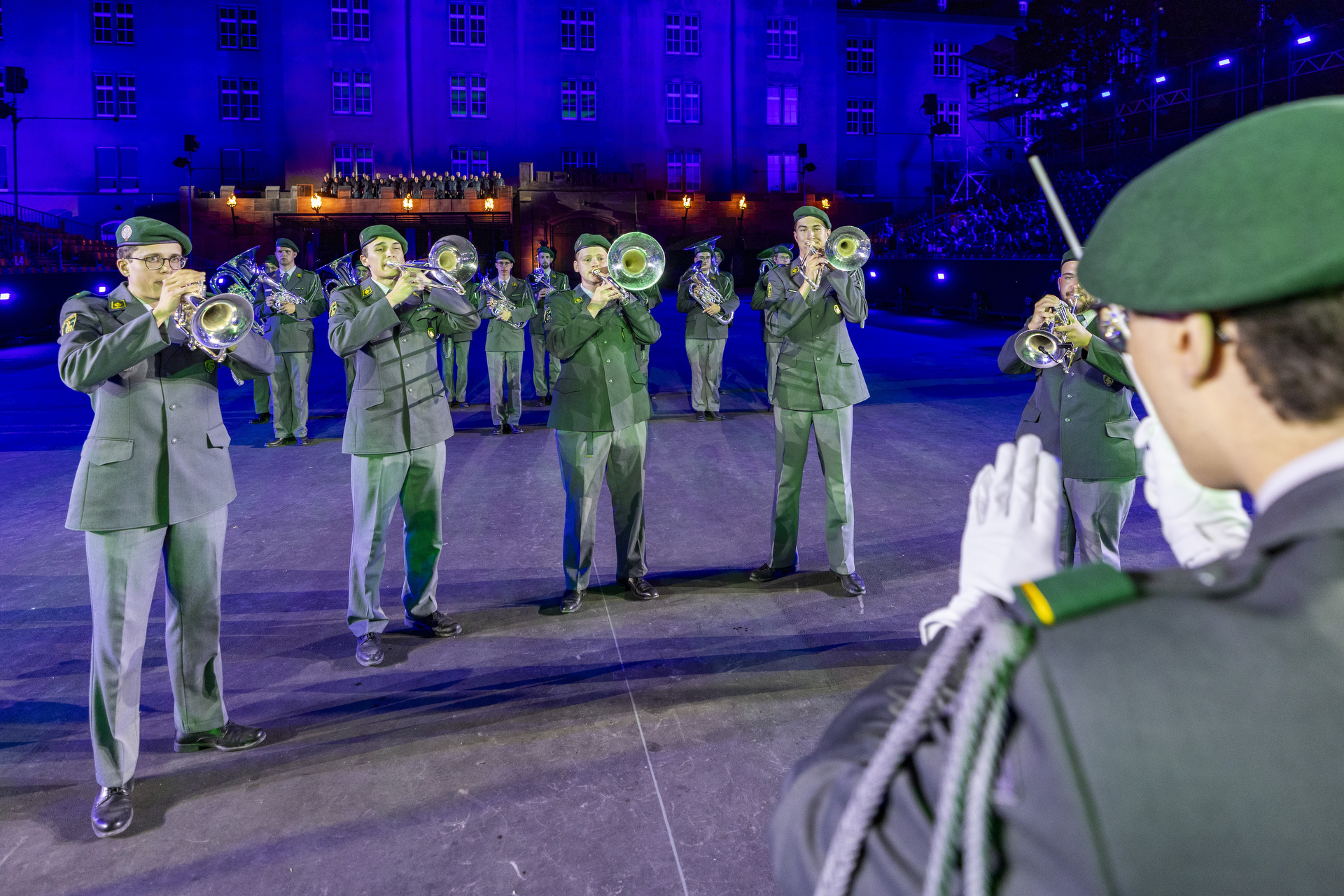 Der Dirigent des Rekrutenspiel RS 16-1/2023 der Schweizer Militärmusik, im Hintergrund der Basel Tattoo Chor